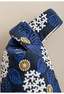 Dettaglio della custodia in tessuto ricamato per tazza, borsa da viaggio floreale.