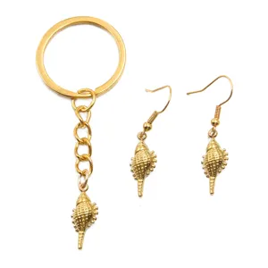 Gros-plan détaillé de pendentif coquillage conque doré, porte-clés et boucles d'oreilles.