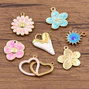Gros plan détaillé de pendentifs breloques DIY bijoux cœur fleur en émail or coloré accessoires.