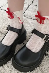 Detailed shot of white hollow lace ruffled socks with red velvet bows for sweet cute Jk style.