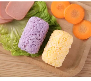 Cylindrical rice ball mold detail shot, showing purple and yellow sushi rolls on a wooden tray.