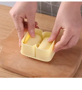 Detailed view of the light yellow two-compartment cylindrical rice ball mold in practical use.