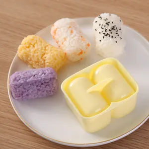Two-compartment cylindrical DIY rice ball mold set with colorful sushi on white plate for home cooking.