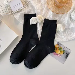 Black mid-calf JK socks with cute white plush angel wings, sweet Lolita style detail shot.