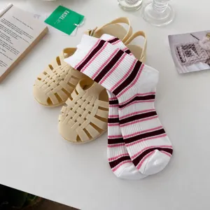 Detail view of retro striped slouch socks paired with beige jelly sandals, styled nicely.