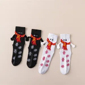 Vue détaillée de chaussettes de Noël magnétiques tendance se tenant la main avec écharpe et flocon.