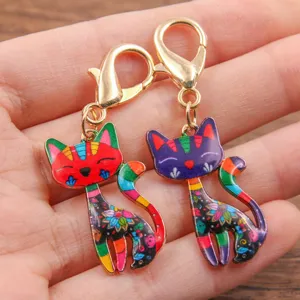 Gros plan de charmants pendentifs chat en émail coloré avec des motifs et des fermoirs dorés.