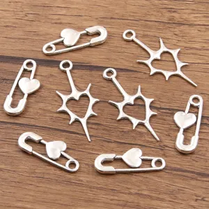Close-up of silver alloy DIY charms with hollow heart safety pins and starburst pendants.