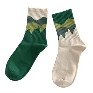 Asymmetrical mountain knit crew socks for women and men, trendy green and white design.