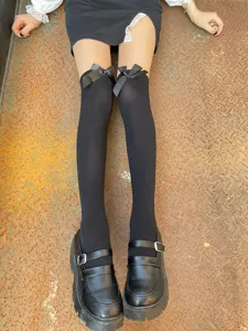 Black over-the-knee socks featuring elegant satin bows, paired with retro Mary Jane shoes.