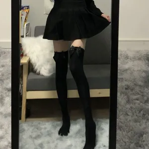 Detail shot of black over-the-knee socks featuring delicate bow accents for stylish JK outfits.