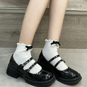Detail view of cute Japanese JK style white ruffled socks with black bows and hollow-out design.