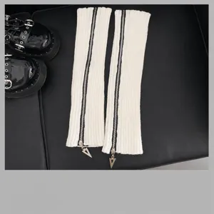 Vue détail de jambières en tricot blanc avec fermeture éclair et pendentif triangle.