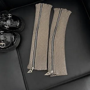 Détail de jambières en tricot gris avec fermeture éclair, texture côtelée et métal.