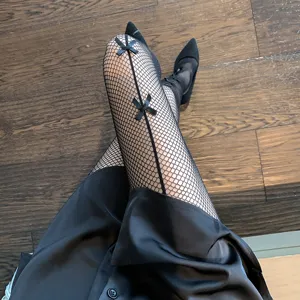 Detailed close-up shot of black fishnet pantyhose featuring cute ribbon bows and back seam.