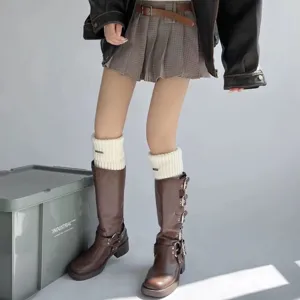 Nahaufnahme von gestrickten Beinstulpen kombiniert mit Lederstiefeln in modernem Studiodesign.
