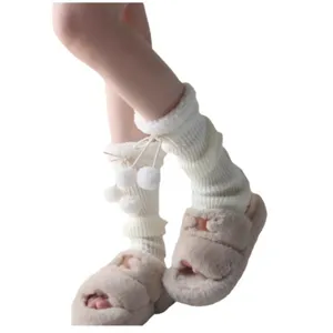 Warm knit leg warmers with plush pom poms for women, cozy winter fashion accessory.