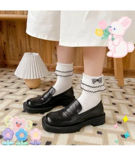 Close-up detail of cute white Lolita socks with black bow and lace trim paired with black loafers.