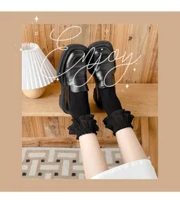 Detail shot of black loafers and frilly ruffled socks, cute Japanese style daily wear close-up.