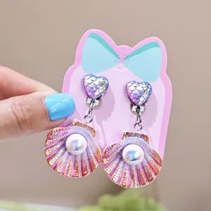 Close-up detail of cute shell pearl clip-on earrings for kids, colorful mermaid scale.