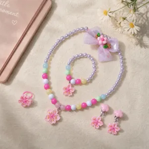 Close up detail of kids princess style beaded necklace bracelet ring and flower hair clip set.