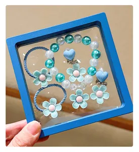 Detail view of cute children flower and pearl bracelet hair tie set in blue display box.