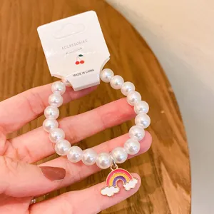 Close-up detail of cute Korean style pearl beaded bracelet with colorful rainbow charm.