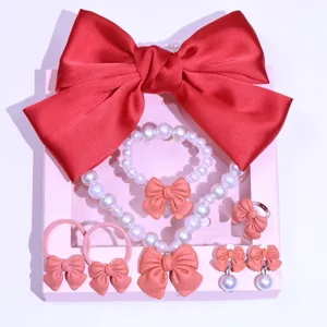 Detailed view of children jewelry set featuring red bow, pearl necklace, bracelet and rings.