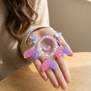 Close-up detail of cute kids mermaid tail bracelet and clip earrings set in pink and purple.