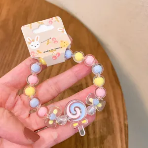 Close-up detail of children candy colored beaded bracelet featuring cute lollipop and bow charms.