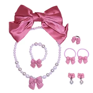 Close-up details of children pink bowknot pearl necklace bracelet ring hair clip set.