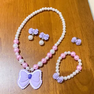 Children pearl jewelry set detail showing necklace, bracelet, earrings and cute purple bow.