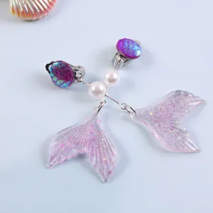 Close-up detail of glittery pink mermaid tail clip-on earrings with faux pearls for kids.