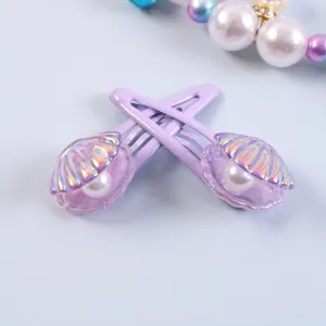 Close-up detail of cute purple shell hair clips with shiny pearl design for sweet girls daily wear.
