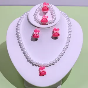 Detail shot of children pearl necklace bracelet ring and earrings set with cute rabbit charms.