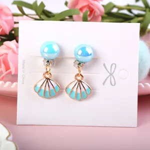 Cute children clip-on earrings detail featuring blue pearl stud and seashell pendant design.