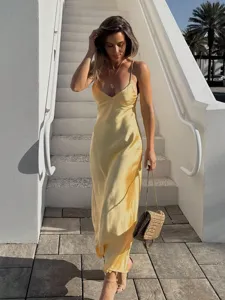Vue détaillée de la robe nuisette en satin de soie jaune, élégante scène extérieure.