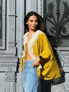 Detail shot showing the delicate white lace patchwork and tie-front design of the yellow cardigan.