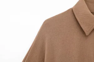 Close-up detail of women's brown long sleeve lapel shirt collar and shoulder fabric.