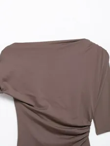 Detail shot of women's brown asymmetrical single-sleeve ruched top, highlighting fabric and drape.