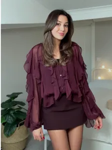 Detailed shot of women's burgundy ruffle chiffon long sleeve blouse in bedroom scene style.