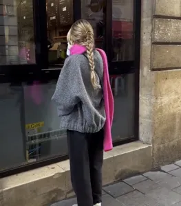 Casual grey knit sweater paired with a vibrant pink scarf for a stylish street look.