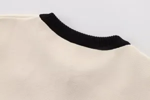 Detailaufnahme des kurzen Damen Strickpullover Kragens, beige und schwarzes Farbblockdesign.