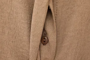 Brown button-up shirt fabric detail close-up showing soft textured material and button.