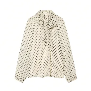 Detailed view of the chic polka dot blouse featuring a graceful bow tie neckline and long sleeves.