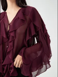 Close-up detail of women's deep red sheer V-neck blouse with dramatic ruffled long sleeves.