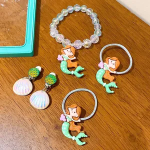 Kids mermaid jewelry set featuring beaded bracelet, hair ties and seashell clip earrings for girls.