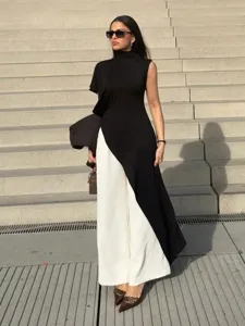 Detailed view of the stylish asymmetric high-neck sleeveless top paired with chic white pants.