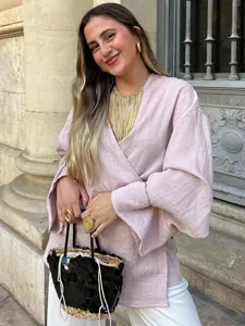 Λεπτομερής λήψη της κομψής ροζ μπλούζας κιμονό που φοριέται σε εξωτερικό χώρο, αστικό στυλ.