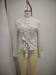 Detailed view of the women's black and white polka dot long sleeve blouse with waist tie.
